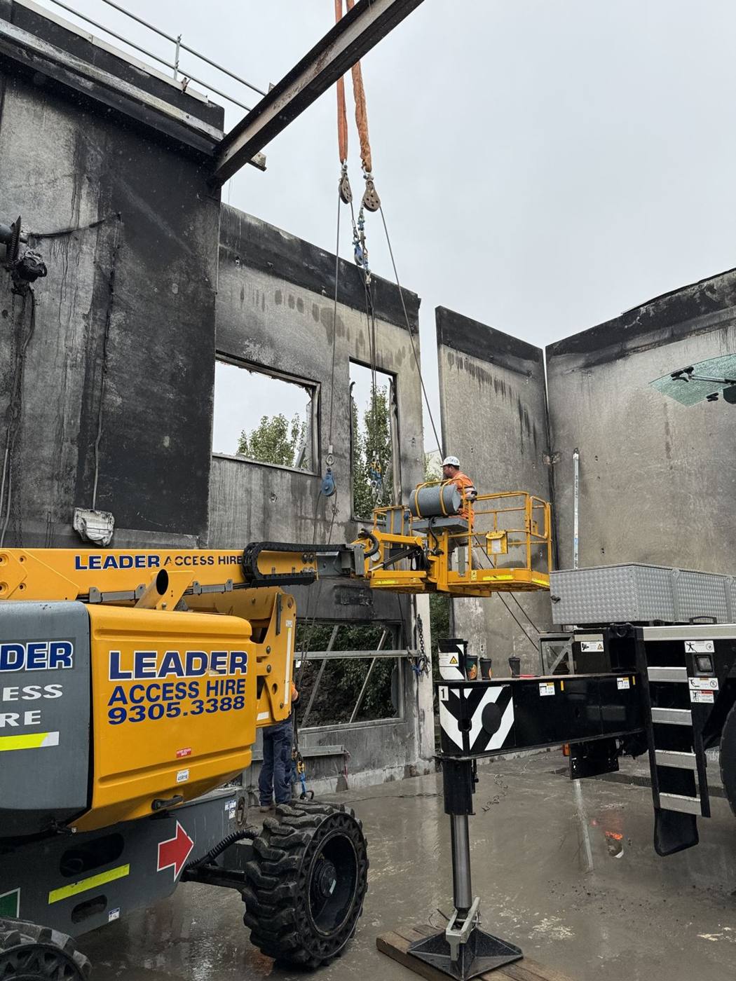 Damaged precast panel being removed by crane from a fire-affected building