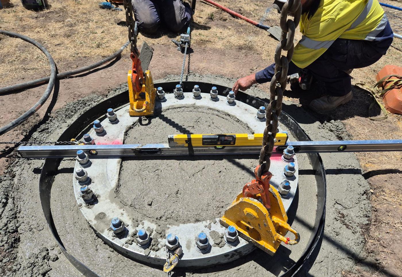 Holding-down bolt cage being set to level on a new footing